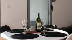 Une table à manger avec une bouteille de vin, des verres et une petite plante.