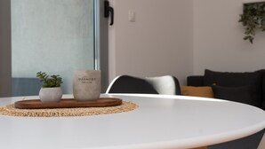 Un espace repas moderne avec une table blanche, une petite plante en pot et un plateau décoratif.