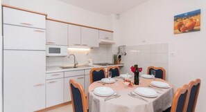 A compact kitchen with white cabinets, a microwave, and a dining area with a table set for four.