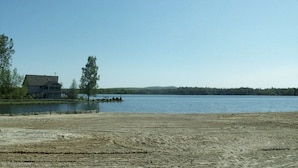 Una propiedad frente al lago con una casa, un área cercada y una vista despejada del lago.