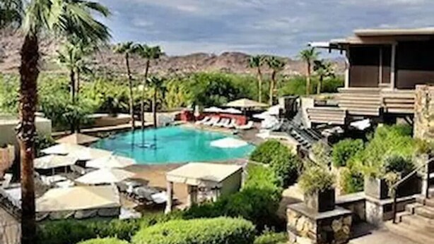 Un resort con piscina, sillas de descanso y palmeras.