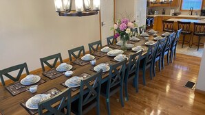 Un comedor con una larga mesa de madera dispuesta para una comida, rodeada de sillas.