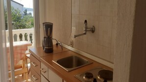 Une cuisine équipée d’un évier, d’une cuisinière et d’une machine à café posée sur le plan de travail.