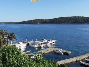 A marina with several boats docked, surrounded by greenery and a clear view of the water. - Apartments Biserka - Two Bedroom Apartment with Terrace and Sea View (Rab)