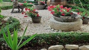 A garden with a statue, potted plants, and a large barrel. - Apartments Biserka - One Bedroom Apartment with Balcony and Sea View (Rab)