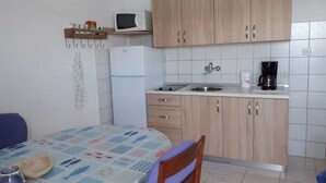 A compact kitchen with wooden cabinets, a microwave, a refrigerator, a sink, and a coffee maker. - Apartments Biserka - One Bedroom Apartment with Balcony and Sea View (Rab)