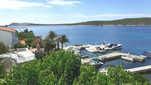 A marina with boats docked, a clear sky, and a hilly landscape in the background. - Apartments Biserka - One Bedroom Apartment with Balcony and Sea View (Rab)