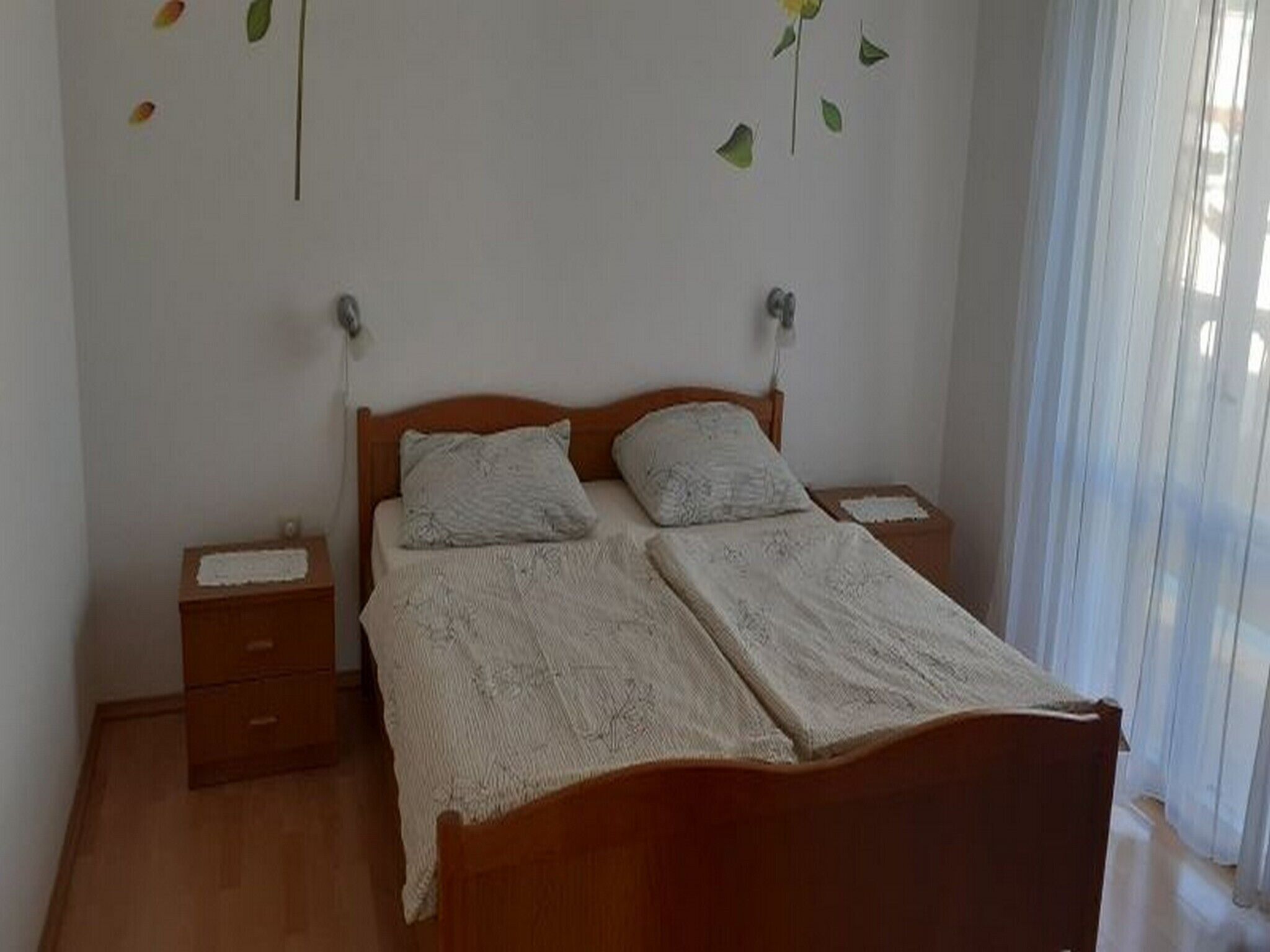 A double bed with a wooden headboard, two bedside tables, and a nightstand.