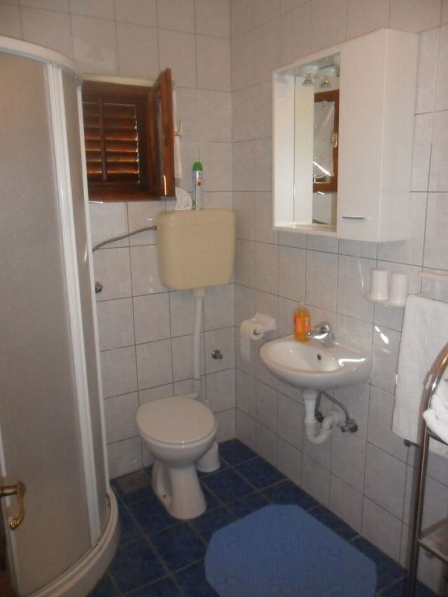 A small bathroom with a toilet, sink, and shower.