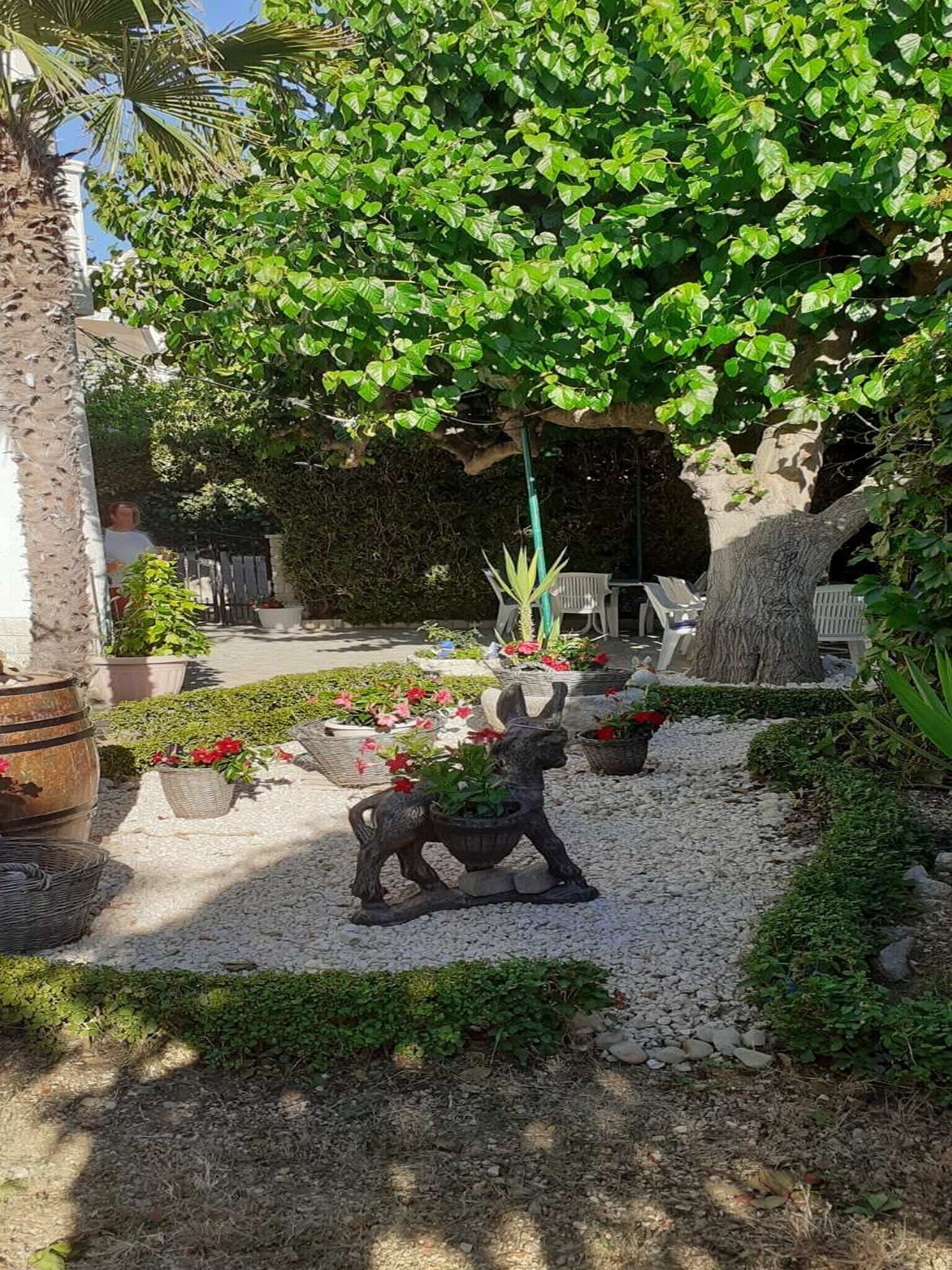 A garden with a statue, potted plants, and a seating area.