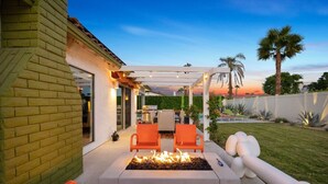 An outdoor patio with a fire pit, orange chairs, and a pergola. - Lush & Tranquil 3BR Palm Springs Oasis Pool & Spa (Palm Springs)