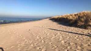 Une plage de sable avec des empreintes et des dunes herbeuses.