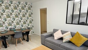 Un salon moderne avec un canapé gris, une table basse en bois et un papier peint à motifs floraux.
