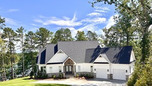 A modern two-story house with a stone foundation, a large front driveway, and a well-maintained lawn. - Carolina’s Cottage Cove-Lake Keowee (Seneca)