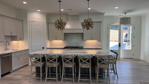 A spacious kitchen with a large island, wooden chairs, and pendant lighting. - Carolina’s Cottage Cove-Lake Keowee (Seneca)