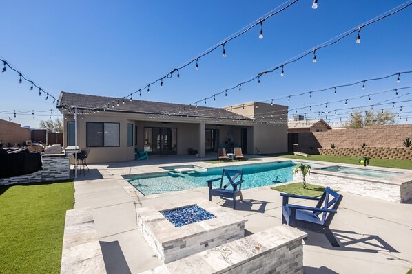 Uma casa moderna com piscina, área de estar externa e luzes pendentes.
