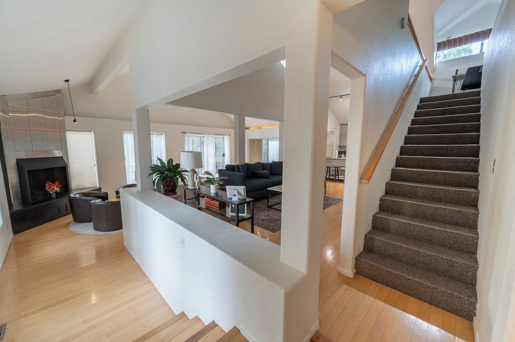 Amplia sala de estar con una escalera, una chimenea y una cocina moderna al fondo.