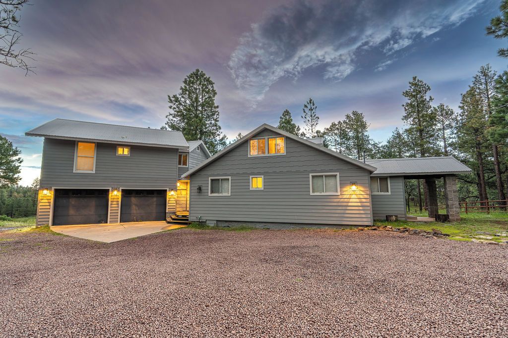 A two-story house with a garage, a covered porch, and a gravel driveway.