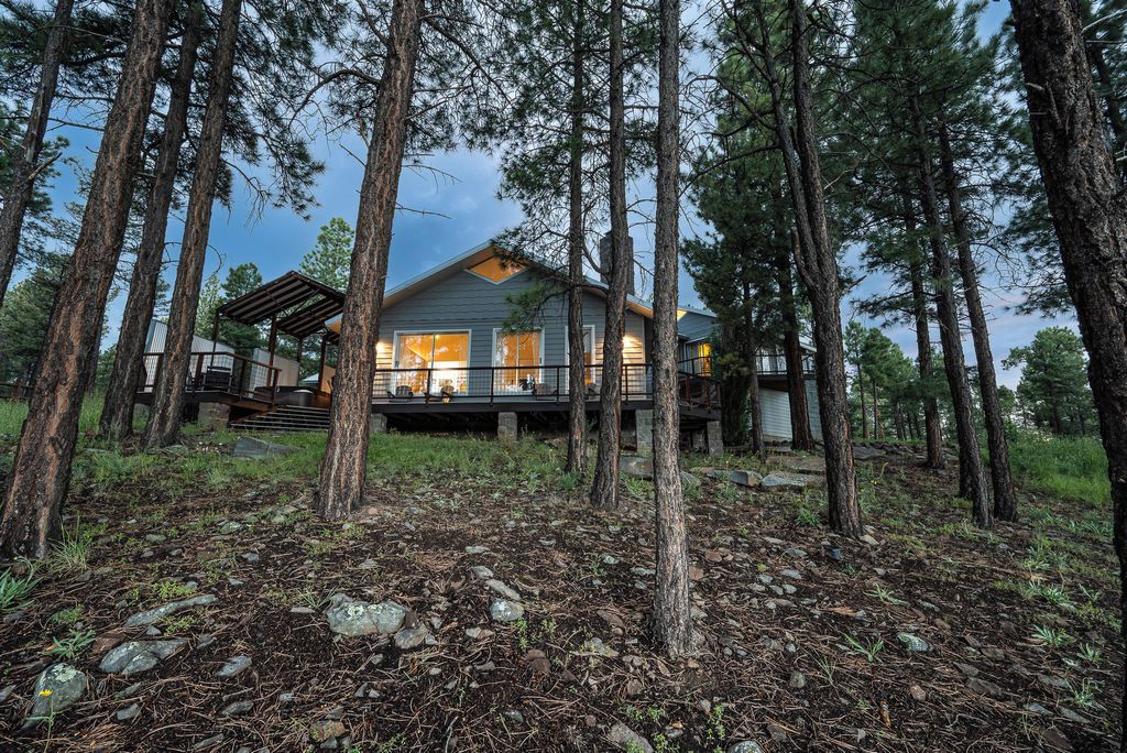 A cabin surrounded by tall trees, with a covered outdoor area and a visible deck.