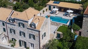 A stone building with a swimming pool, outdoor seating, and a well-maintained garden.