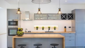 A modern kitchen with a central island, built-in oven, and pendant lighting.