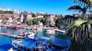 A harbor with boats docked, a prominent tower, and buildings on a hillside. - Villa Citronella Boutique Hotel (Antalya)