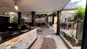 An outdoor cafe area with stone walls, wooden furniture, and a central seating arrangement. - Villa Citronella Boutique Hotel (Antalya)