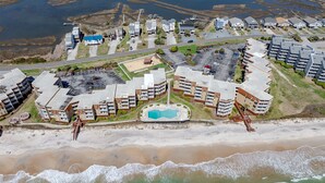 An aerial view of a coastal residential area with modern apartment buildings, a swimming pool, and a beach. - Oceanfront views, Beachfront condo, The Driftwood! (north topsail beach)