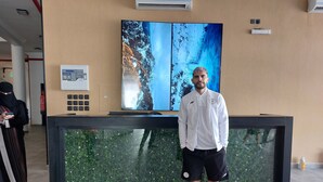 A man standing in front of a reception desk with a large digital screen displaying a waterfall image. - Karims'Hotel (Al Majmaah)