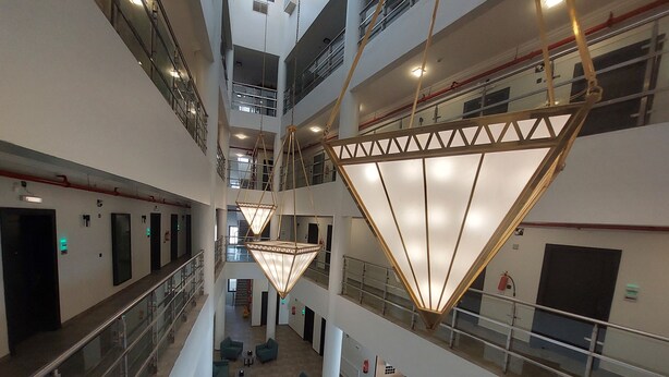 A multi-level atrium with a central open space, glass railings, and modern lighting fixtures. - Karims'Hotel (Al Majmaah)