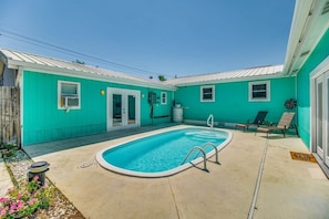 Een turquoise huis met een zwembad, een deur en een raam.