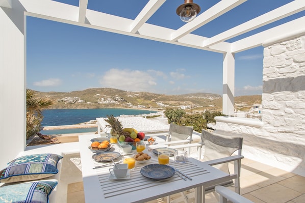 Une table dressée pour le petit-déjeuner, avec vue sur la mer et les collines.