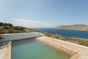Une piscine avec vue sur la mer et les collines.