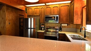 A kitchen with wooden cabinets, stainless steel appliances, granite countertops, and a built-in oven.