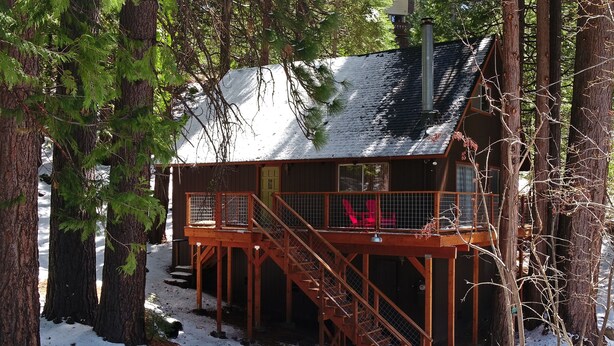 A cabin with a wooden deck and stairs leading to a covered area.