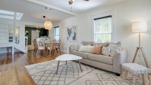 A spacious living room with a white sofa, a coffee table, and a dining area with chairs.