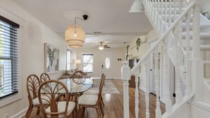 A dining area with a round table and chairs, a staircase with white balusters, and a ceiling fan.