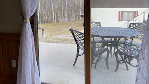 Een kamer met een schuifdeur die uitkomt op een terras met een tafel en stoelen.