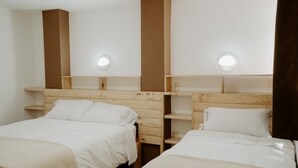 Una habitación con dos camas, cabeceros de madera y estanterías empotradas.
