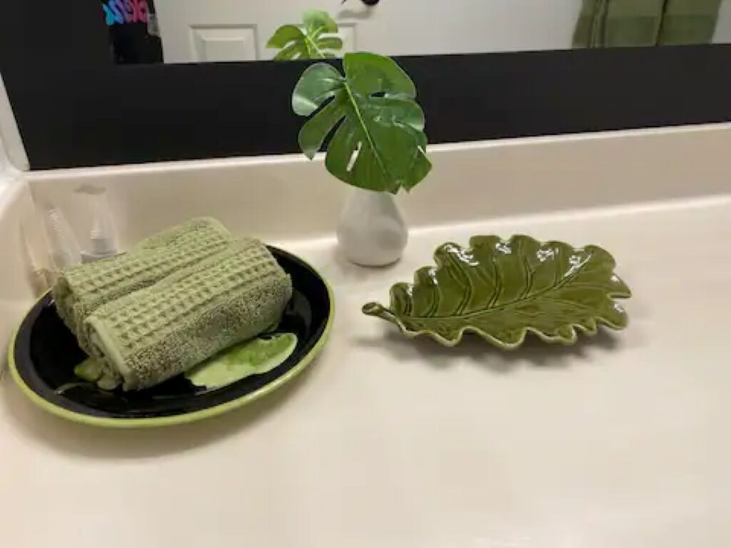 Un meuble-lavabo dans une salle de bain, avec une serviette, une feuille décorative et une plante en pot.