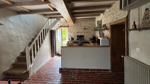 Een rustieke keuken met zichtbare balken, een stenen muur en een tegelvloer.
