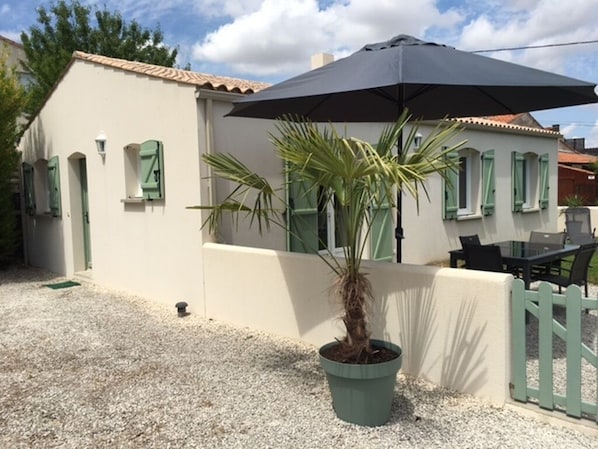 A building with a tiled roof, a potted palm tree, and a black umbrella.