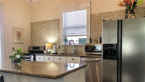 Una cocina con isla central, electrodomésticos de acero inoxidable, microondas y refrigerador.