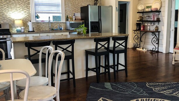 Una cocina con encimera de granito, electrodomésticos de acero inoxidable y una zona de comedor con taburetes de bar.