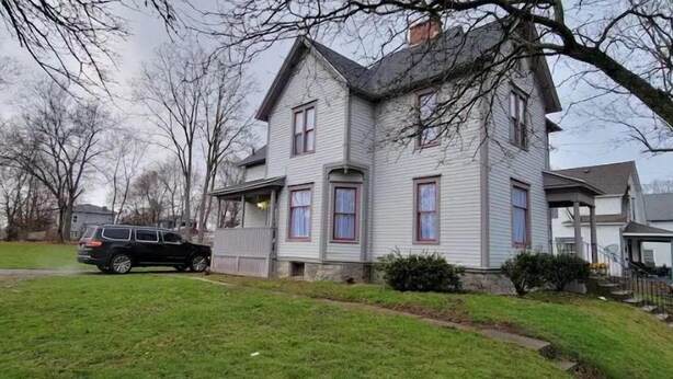 A two-story house with a front porch, a garage, and a small garden area. - The Wesley - Historic 1890 Victorian, Second Floor (Albion)