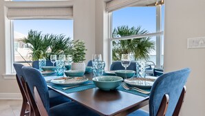 Een eettafel met blauwe stoelen, glanzend servies en een blauwe schaal als decoratie.