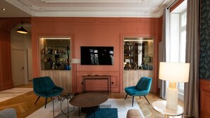 A living room with a large flat-screen TV, two teal armchairs, a coffee table, and a sofa.