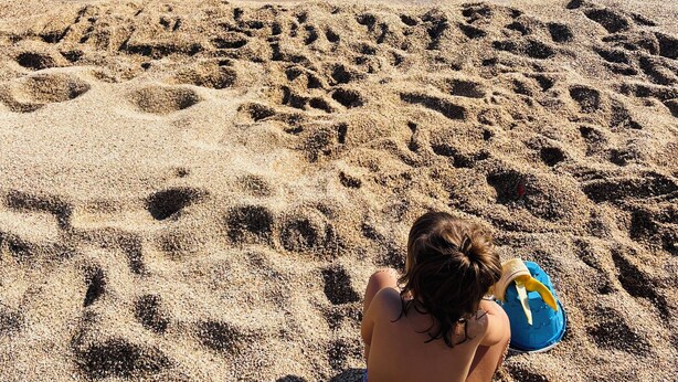 A sandy beach with footprints leading to the water.