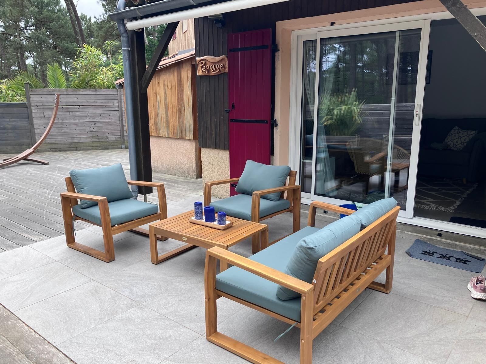 A patio with wooden furniture, including a sofa and chairs, and a table with candles.