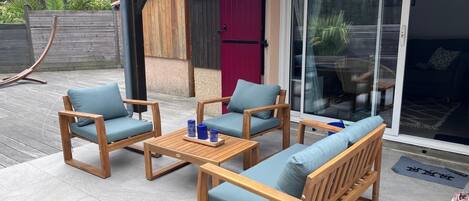 A patio with wooden furniture, including a sofa and chairs, and a table with candles.